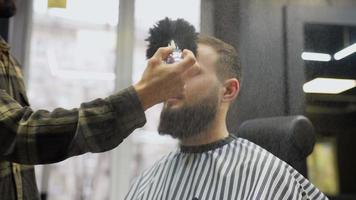 el peluquero empolva la cara de un cliente masculino con un cepillo grande video