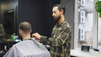 coiffeur coupe l'arrière de la tête des cheveux et du cou du client masculin avec un peigne et une tondeuse video