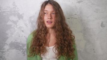 Young woman with long red curly hair speaks and laughs looking toward camera video