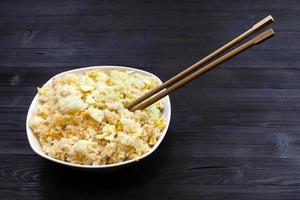 bowl with Fried Rice with chopsticks on dark table photo