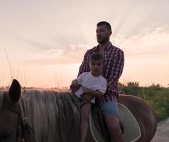 Father and son enjoy riding horses together by the sea. Selective focus photo