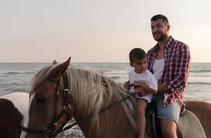 Father and son enjoy riding horses together by the sea. Selective focus photo