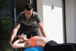 woman and personal trainer doing exercise with pilates ball photo