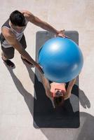 woman and personal trainer doing exercise with pilates ball photo