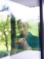 young woman drinking morning coffee by the window photo