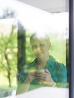 young woman drinking morning coffee by the window photo