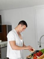 hombre cocinando en casa preparando ensalada en la cocina foto