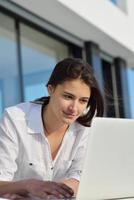 relaxed young woman at home working on laptop computer photo