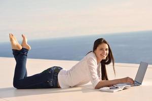 relaxed young woman at home working on laptop computer photo