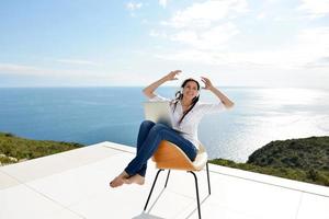 relaxed young woman at home working on laptop photo