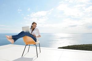 relaxed young woman at home working on laptop photo