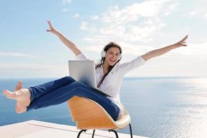 relaxed young woman at home working on laptop photo