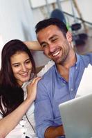 relaxed young couple working on laptop computer at home photo