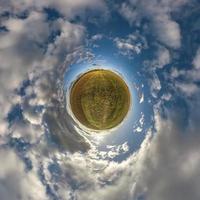 tiny planet in blue sky with beautiful clouds. Transformation of spherical panorama 360 degrees. Spherical abstract aerial view. Curvature of space. photo