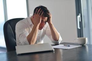 joven hombre de negocios frustrado que trabaja en una computadora portátil en casa foto