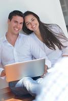 young couple using laptop at home photo