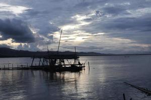 silhouette of a traditional fishing hut by the lake photo