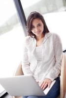 relaxed young woman at home working on laptop computer photo