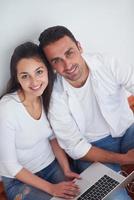 relaxed young couple working on laptop computer at home photo