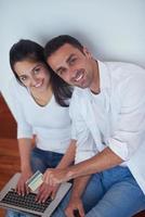 relaxed young couple working on laptop computer at home photo