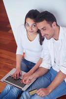 relaxed young couple working on laptop computer at home photo