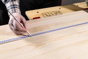 carpenter with pencil marks size on wooden board photo