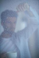 relaxed young man drink first morning coffee withh rain drops on window photo