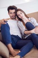 young couple watching tv at home photo