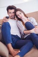 young couple watching tv at home photo