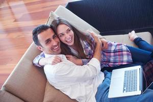 relaxed young couple working on laptop computer at home photo