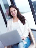 relaxed young woman at home working on laptop computer photo