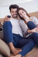 young couple watching tv at home photo