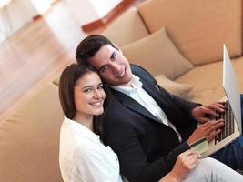 relaxed young couple working on laptop computer at home photo