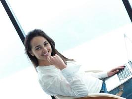 relaxed young woman at home working on laptop computer photo