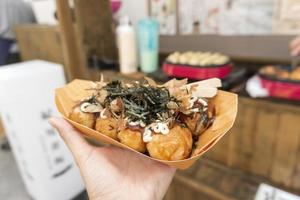 Takoyaki octopus balls on hand, Japanese snack. photo