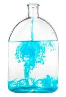 blue watercolour dissolves in water in glass flask photo