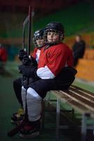 niños jugadores de hockey sobre hielo en un banco foto