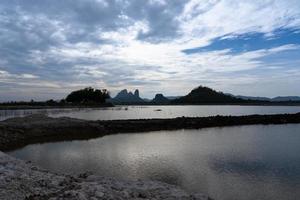 Landscpae of Mountain and Lake with Silhouette of People Working in Field in Lopuri Thailand photo