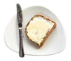 Sándwich con mantequilla y cuchillo en plato aislado foto