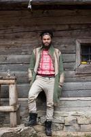 portrait of young hipster in front of wooden house photo