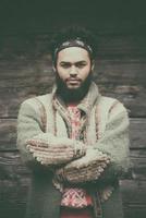 portrait of young hipster in front of wooden house photo