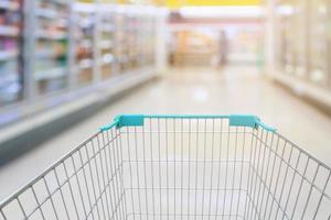 Shopping cart view with milk and yogurt product shelves aisle in supermarket photo