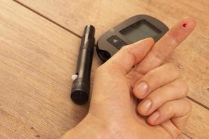 a drop of blood on a woman's finger to measure glucose using glucometer photo