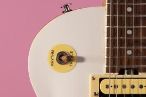front part of the body of a white electric guitar on pink background
