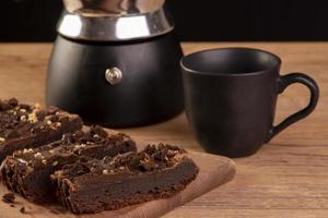 algunas rebanadas de brownie en madera, una cafetera y una taza de café foto