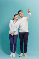 Young asian couple isolated on blue background pointing finger to the side photo