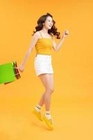 Big Sales. Girl Running With Shopping Bags Over yellow Background, photo
