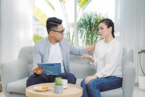 Smiling young Asian male psychiatrist talking to young woman at his office. photo