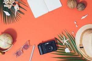 Flat lay beach accessories sunglasses, hat, camera with palm branches and shells. photo