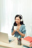 Chica asiática inteligente escritorio trabajo remoto portátil reloj seminario bebida taza de bebida en casa interior foto